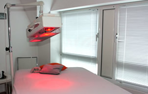 Eingeschalteter Rotlicht-Strahler über Liege zur Thermotherapie